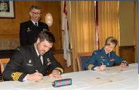 Under the watch of RAdm John Newton, Capt(N) Angus Topshee, Base Commander CFB Halifax, and Col Darlene Quinn, Comd CF RP Ops Gp, sign the real property transfer in Halifax on March 23, 2015. // Sous le regard attentif du Cam John Newton, le Capv Angus Topshee, commandant de la BFC Halifax et le Col Darlene Quinn, Cmdt du Groupe des opérations immobilières des FC, signent le transfert des biens immobiliers à Halifax le 23 mars 2015.