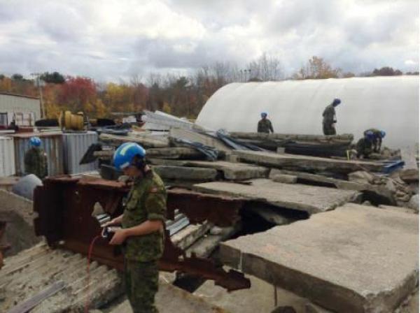 Members of RCAF USAR traverse a rubble pile using a DELSAR to detect victims (Photo by Capt M Sukstorf)