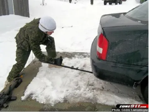A sapper inspects the undercarriage of a vehicle for booby traps.