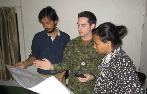 MCpl Denis Carièrre, a DART geomatics technician explains mapping details to Prabhas Pokharel and Megha Shrestha, both volunteers for Kathmandu Living Labs. // Le CplC Denis Carierre, un technicien en géomatique de l’EICC explique les détails du processus de cartographie à Prabhas Pokharel et Megha Shrestha, deux bénévoles des laboratoires vivants de Kathmandu.