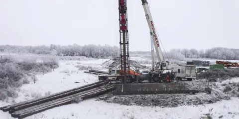 Battling winter conditions, contractors prepare for the installation of the first circular pile that secures the bridge // Luttant contre les conditions hivernales, les entrepreneurs se préparent à installer le premier pieu circulaire qui sécurisera le pont