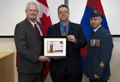 Elie Saydeh receiving a certificate for 25 years of service in the federal public service from Jaime Pitfield, ADM(IE) with CWO Caouette. // Elie Saydeh, recevant son certificat pour ses 25 années de services au sein de la Fonction publique fédérale des mains du SMA(IE), M. Jaime Pitfield avec de l’Adjuc Caouette.